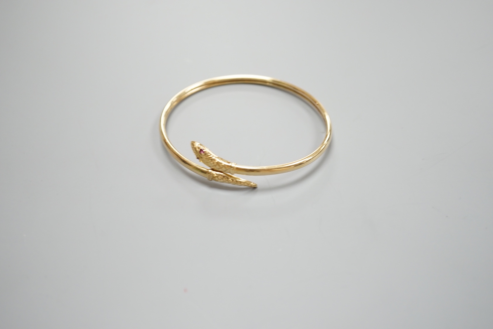 A modern 375 and gem set serpent bangle, 11.3 grams.